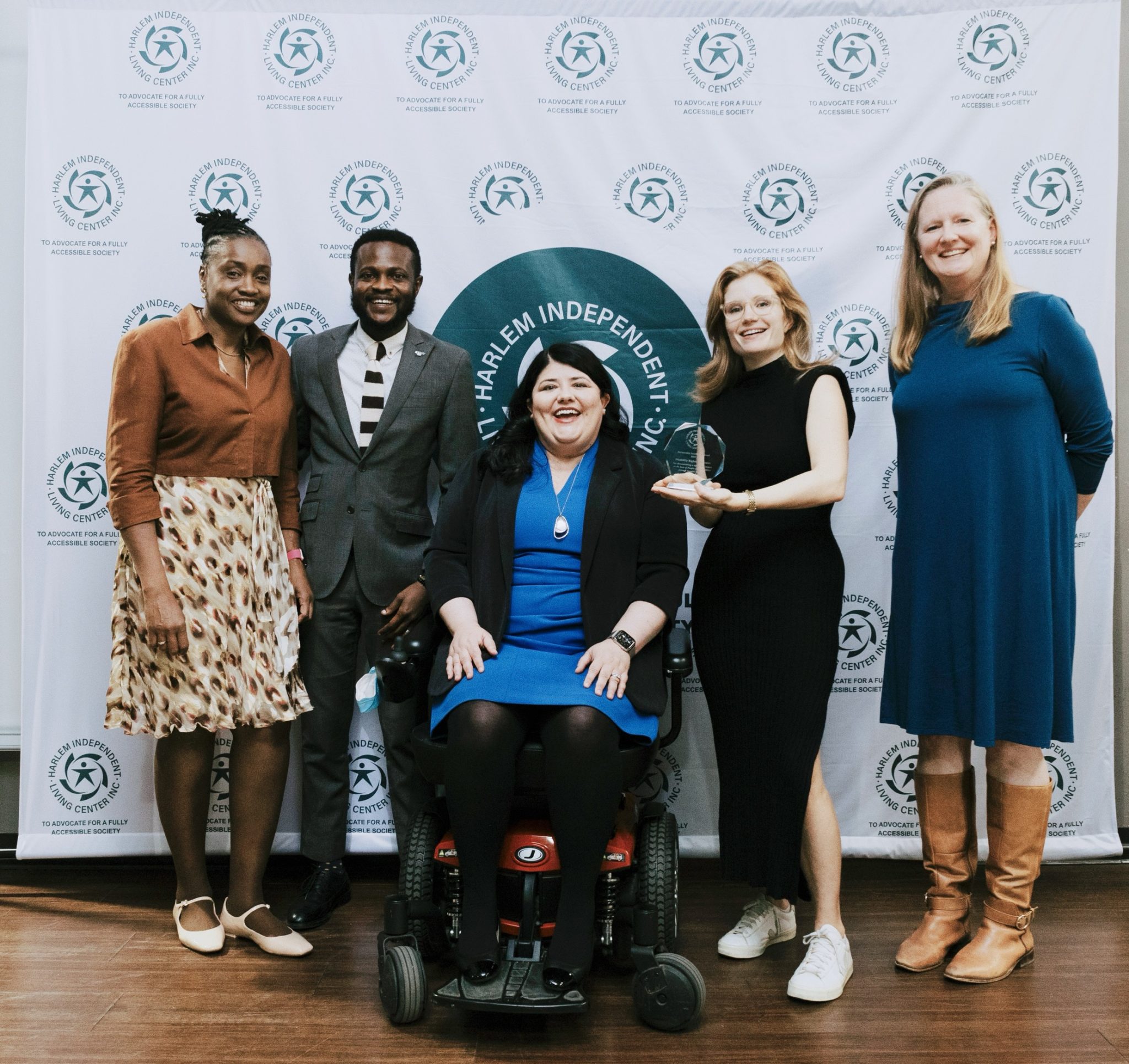 A photo of a group of people from Harlem Independent Living Center (HILC) and Disability Rights Advocate (DRA). One of the women pictured is holding an award DRA received from HILC.